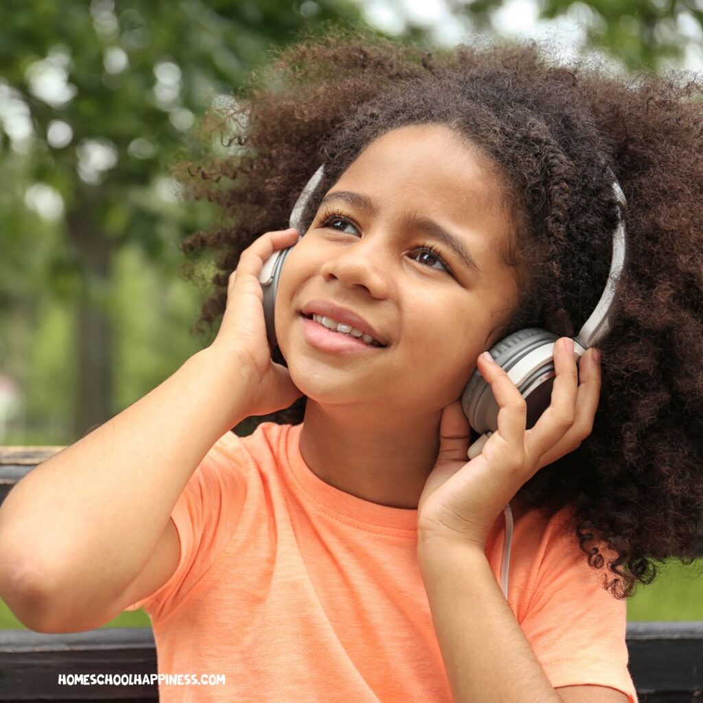 Young girl listens to headphones outdoors, representing auditory learners exploring during summer break.